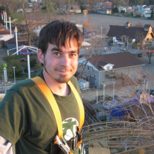 man wearing harness standing on top of roller coaster