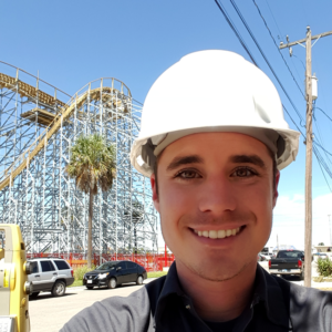 man wearing hard hat standing in front of wooden roller coaster