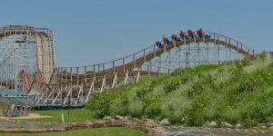 airplane-themed wooden roller coaster goes over hill