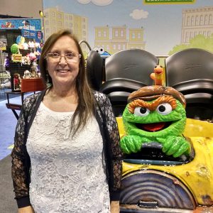 woman stands next to oscar roller coaster car